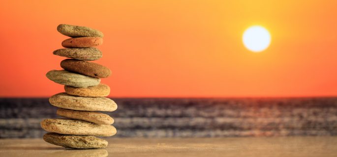 Zen stones stacked on sea background at sunset